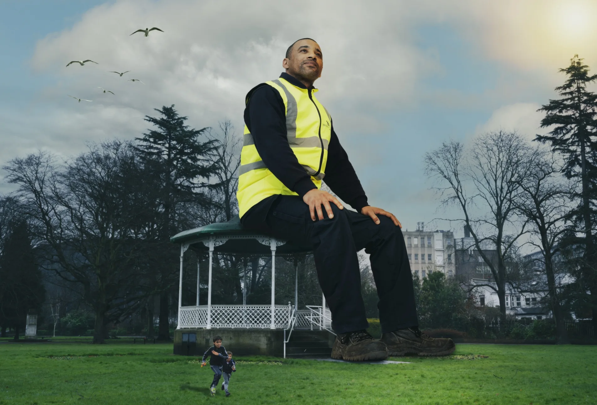 Giant man sits on top of a park bandstand