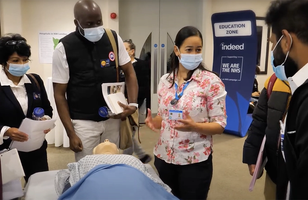 NHS England - A female nurse with a patient teaching 2 men and a lady